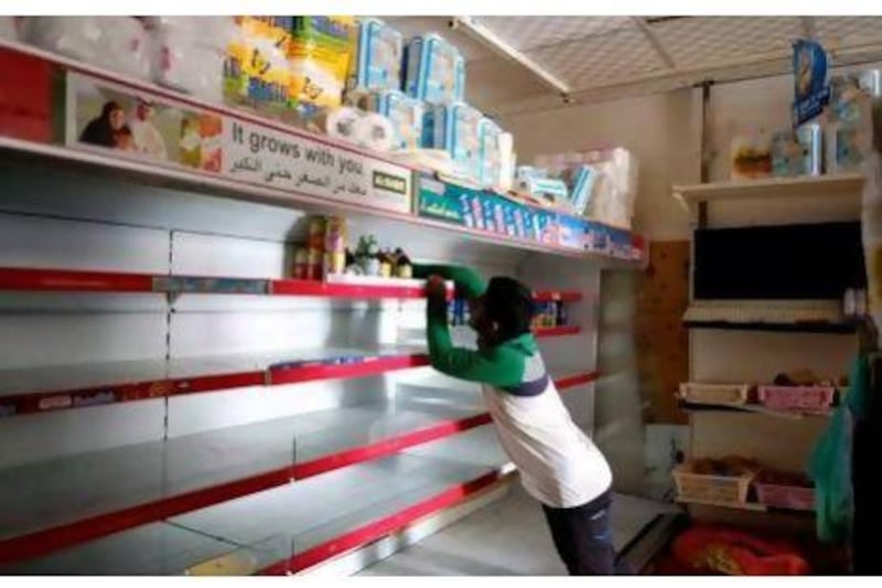 A staff member at the Corniche Al Madina grocery in Al Nahda, Sharjah, clears the shelves of perishable goods as the building in which it operates has been without electricity for six days.