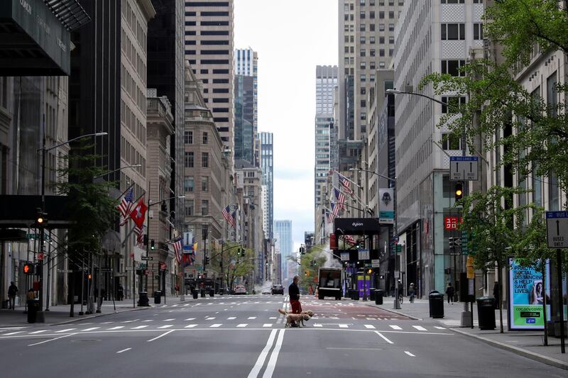 A man walks dogs across a nearly empty 5th Avenue and closed luxury retail stores in Manhattan, New York City. Reuters
