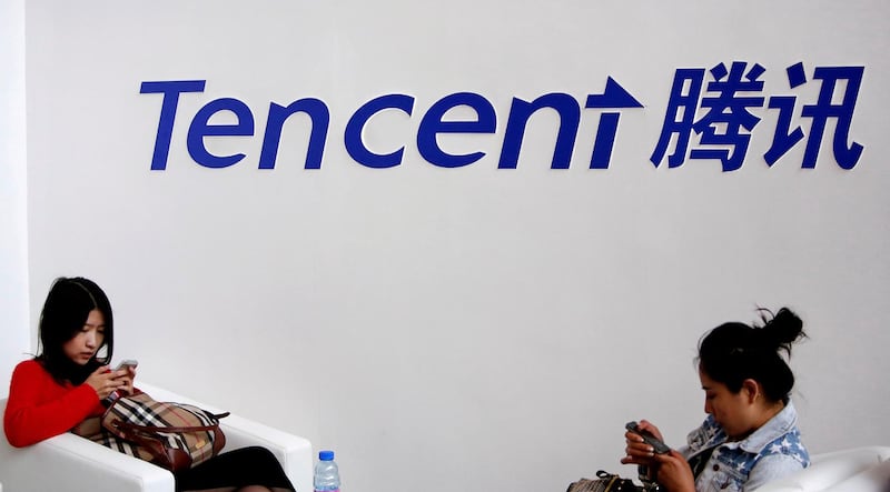 FILE PHOTO: Visitors use their smartphones underneath the logo of Tencent at the Global Mobile Internet Conference in Beijing May 6, 2014. REUTERS/Kim Kyung-Hoon/File Photo