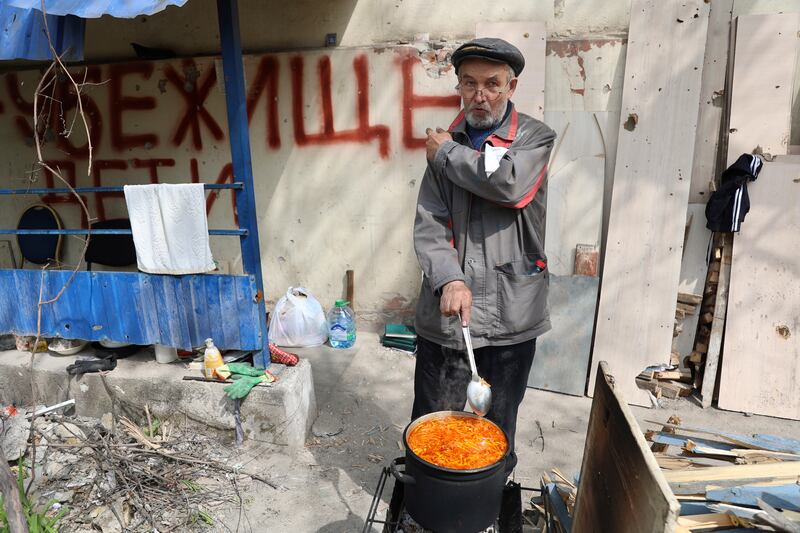 A man outside his house in Mariupol, in territory under the government of the so-called Donetsk People's Republic, eastern Ukraine. The sign reads 'Bomb shelter, children'. AP