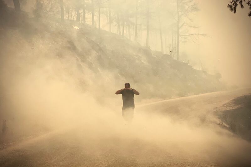 A walks through smoke from burnt out trees near the town of Manavgat.