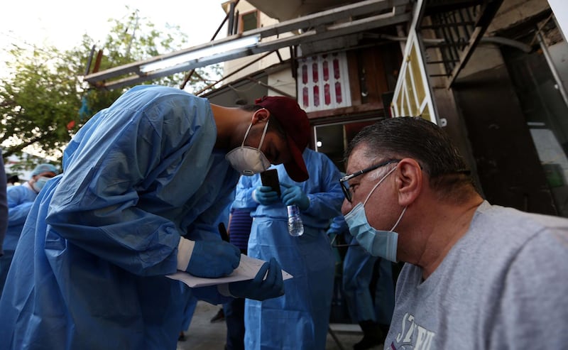 Iraqi medical specialists take a blood sample from a man for a coronavirus test in Baghdad's Karada district. EPA