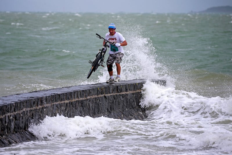 A man stands on a breakwater with his bike along the waterfront in Auckland. AP