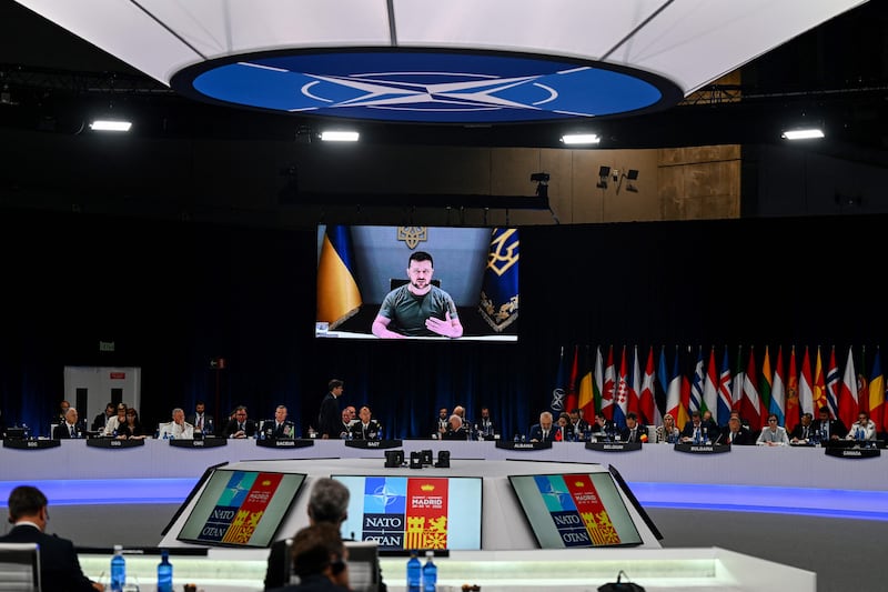 Ukraine's President Volodymyr Zelensky appears on a giant screen as he delivers a statement at the start of the first plenary session of the NATO summit at the Ifema congress centre in Madrid, on June 29, 2022.  (Photo by GABRIEL BOUYS  /  AFP)