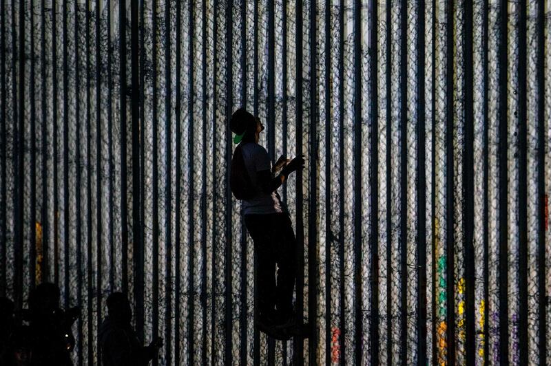 A man climbs  the Mexico-US border fence in Playas de Tijuana, Baja California state, Mexico.   AFP