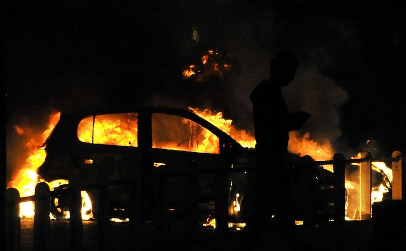 A man walks past a burning car on a street in Ealing, London August 9, 2011. Looting by groups of hooded youths spread to Ealing in west London and Camden in the north of the British capital late on Monday, the third night of violence which police have blamed on criminal thugs.  REUTERS/Toby Melville (BRITAIN - Tags: CRIME LAW CIVIL UNREST) *** Local Caption ***  PNN41_BRITAIN-RIOT-_0808_11.JPG
