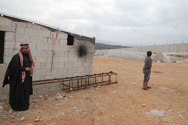 Syrian Abu Jaber stands next to a ladder which he created to climb over the Turkish border wall at an informal camp in Kafr Lusin village in Syria's northwestern province of Idlib. AFP