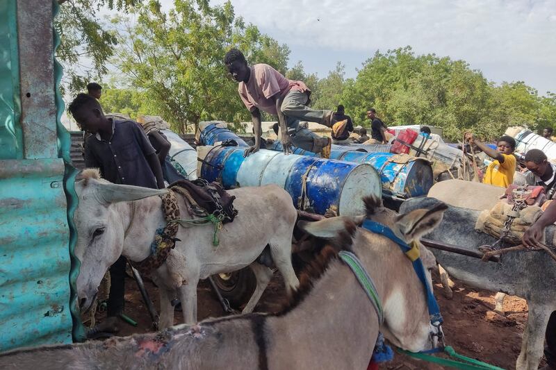 People use makeshift donkey-drawn tanks to re-supply with water in an open market in Gedaref state in eastern Sudan.  AFP