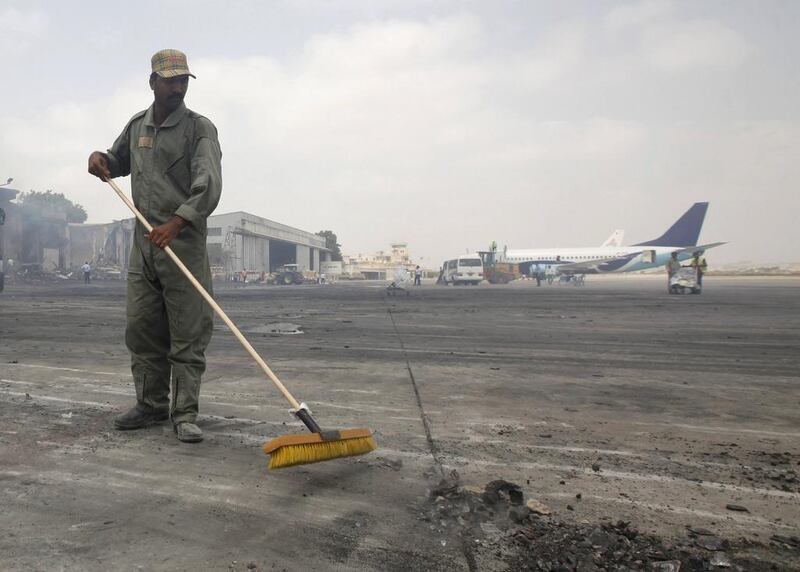 A man clears debris from the tarmac of Jinnah International Airport in the aftermath of the attack. Athar Hussain/Reuters