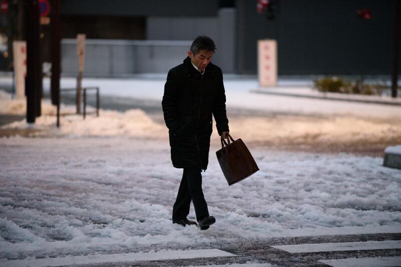 A morning commuter walks across a snow-covered street in Tokyo, Japan, on Tuesday. Akio Kon / Bloomberg