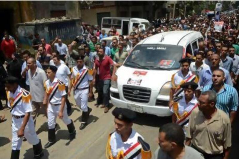 Egyptian policemen march with a vehicle carrying the body of a comrade, killed in Cairo on Monday in clashes outside the Republican Guard headquarters that killed more than 50 people.