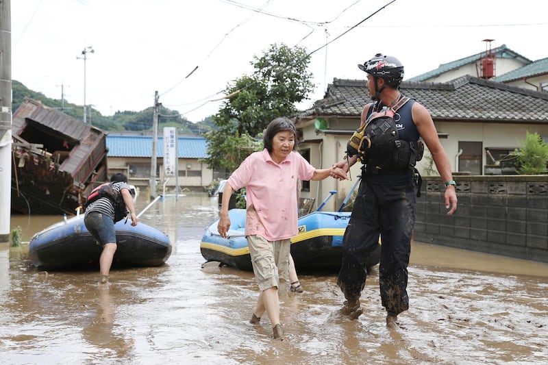 A stranded woman is rescued following a heavy rain in Hitoyoshi, Kumamoto prefecture, southern Japan. Kyodo News via AP