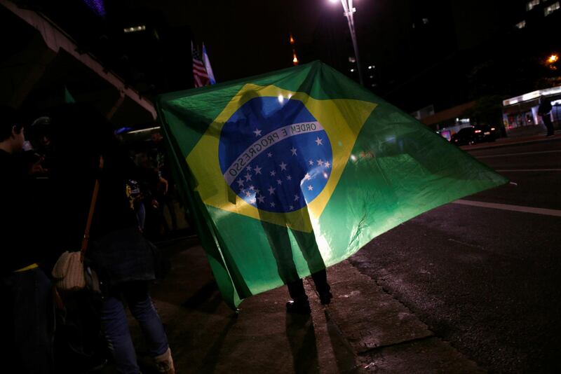A man walks holding the national flag, in Sao Paulo. Reuters