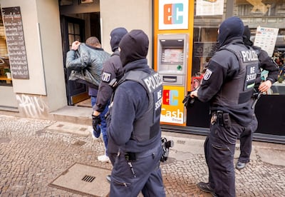 Armed and masked police escort a man in front of a building in Berlin's Neukoelln district during raids against organized clan criminality on February 18, 2021 in the German capital. - Several hundred police officers carried out a large-scale raid in Berlin and the federal state of Brandenburg on February 18, 2021 and detained two suspects following violent clashes between rival gangs in the German capital last autumn, according to police and state prosecutors. They added that the investigation also related to violent "clan clashes" in November 2020 between "members of a family of Arab origin and Russian nationals of Chechen background". (Photo by Odd ANDERSEN / AFP)