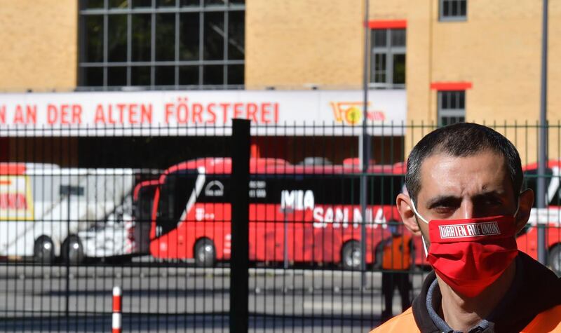 A volunteer wearing a face mask stands next to the entrance to the Alte Foersterei stadium. AFP