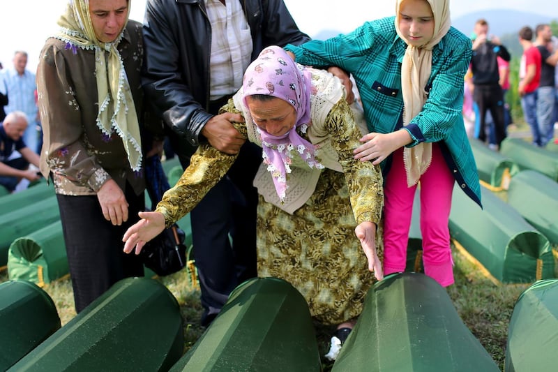 Bosnian women by the coffins of their relatives at the Potocari Memorial Centre during the burial of the remains of 409 newly-identified Bosnian Muslims as part of a memorial ceremony to mark the 18th anniversary of the Srebrenica Massacre in Srebrenica, Bosnia and Herzegovina July 11, 2013. EPA