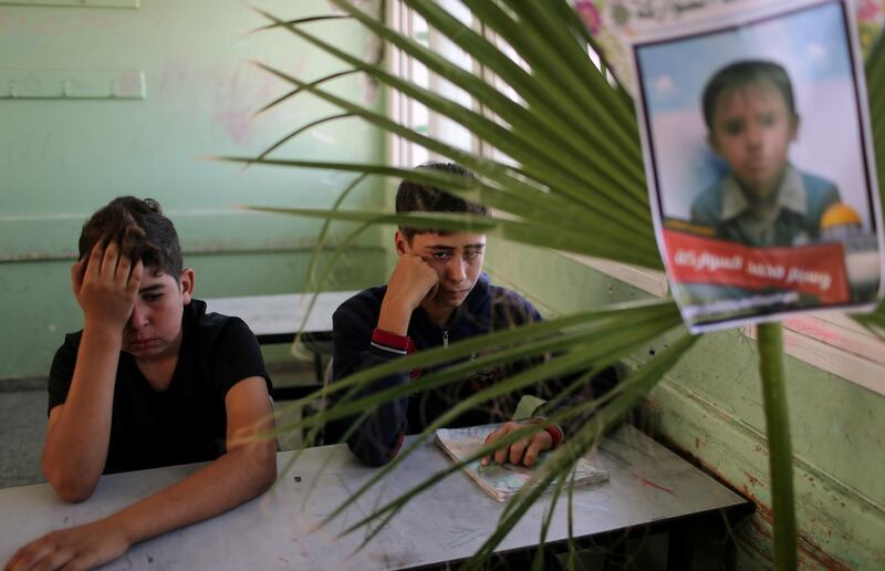 Classmates of Palestinian schoolboy Waseem Abu Malhous, who was killed in Gaza, react as Abu Malhous' picture is seen on his chair in his classroom in a school in the central Gaza Strip. Reuters