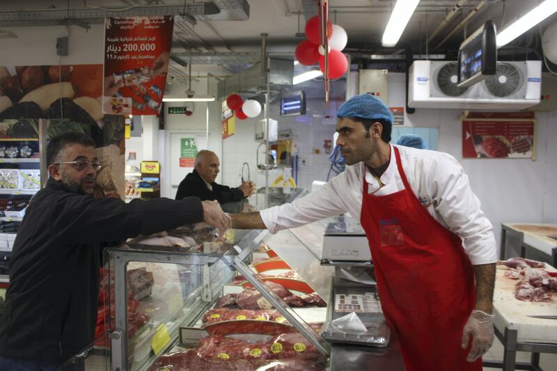Syrian refugee Mansour Mafalani serves a customer at a Carrefour supermarket in Amman on October 31, 2017. Mafalani is one of 34,000 Syrian refugees granted work permits by Jordan this year. Taylor Luck for The National