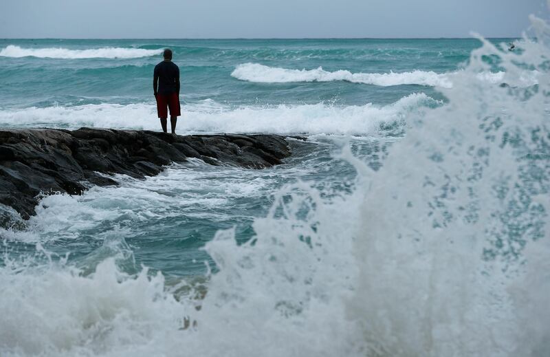 A man stands along the beach as waves crash in Honolulu, Hawaii. John Locher AP Photo
