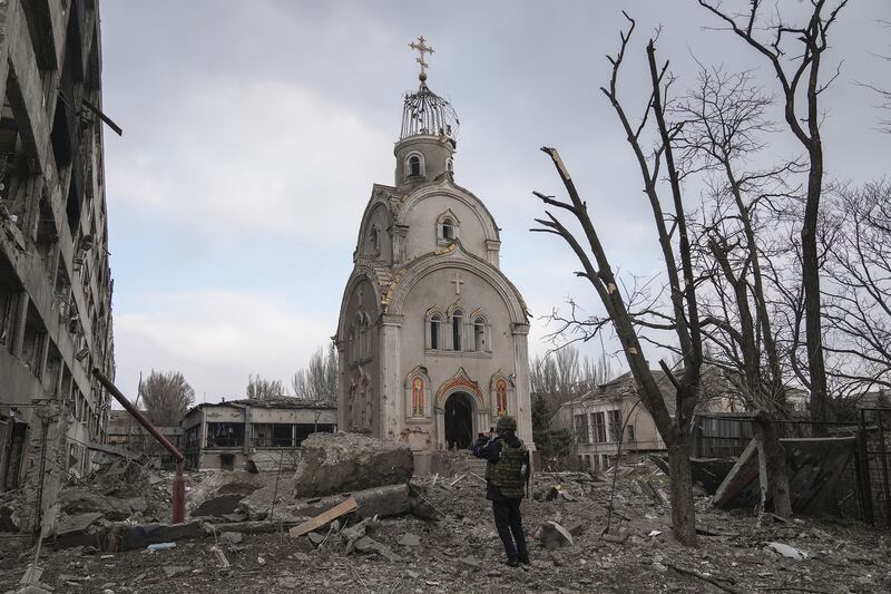 A Ukrainian serviceman taking a photograph of a church in a residential district after shelling in Mariupol. Photo: Evgeniy Maloletka / Associated Press
