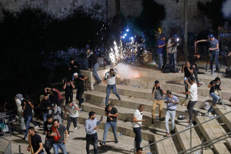 Palestinians run for cover as Israeli police officers fire stun grenades during clashes at Damascus Gate outside Jerusalem's Old City. AP Photo