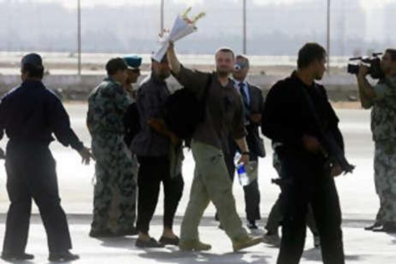 A European tourist, who was taken hostage by bandits in the Egyptian desert 10 days ago and rescued today by the Egyptian army, waves a bunch of flowers as he is escorted across the tarmac of the Army's east Cairo base on September 29, 2008, after arriving their by military transport plane. A group of European tourists and their guides snatched by armed bandits in a remote desert 10 days ago were freed unharmed in a pre-dawn raid by Egyptian Special Forces today, officials said. AFP PHOTO/KHALED DESOUKI *** Local Caption ***  373431-01-08.jpg