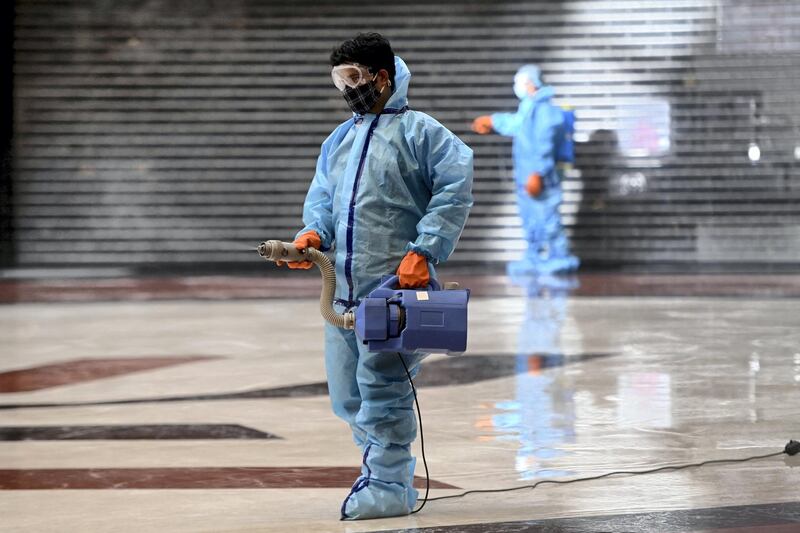 Workers wearing protective gears as a preventive measure against the Covid-19 coronavirus, sanitize the interiors of the Select Citywalk mall in New Delhi on June 6, 2021, after authorities announced the easing of the lockdown in the Indian capital. (Photo by Money SHARMA / AFP)