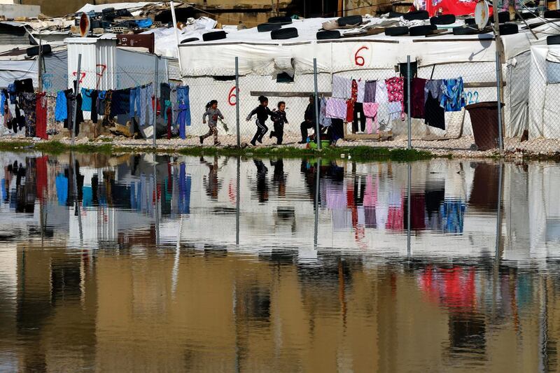 Children play outside as their tents are reflected in a pool of rain water at a refugee camp, in Bar Elias, Lebanon. AP Photo