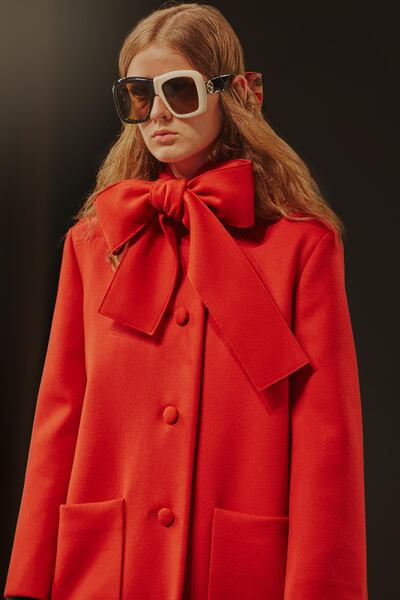 A heavy coat is given a playful bow at the neck, while mismatched sunglasses make this pure Gucci