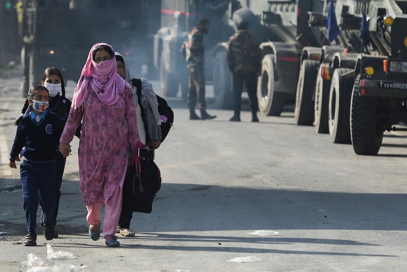 Women and schoolchildren walk past Indian soldiers on the outskirts of Srinagar, Kashmir. AFP