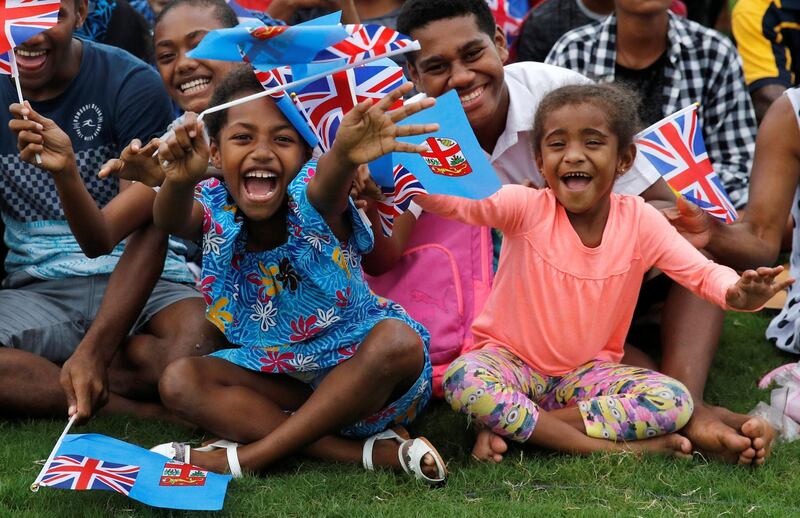 Children smile and wave British and Fijian flags. Reuters