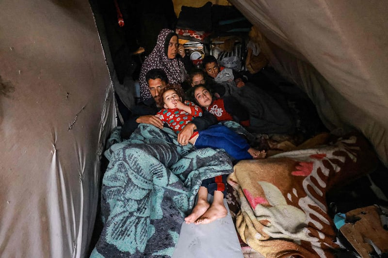 Palestinians rest in their makeshift tent at a camp set up at a school in Rafah. AFP