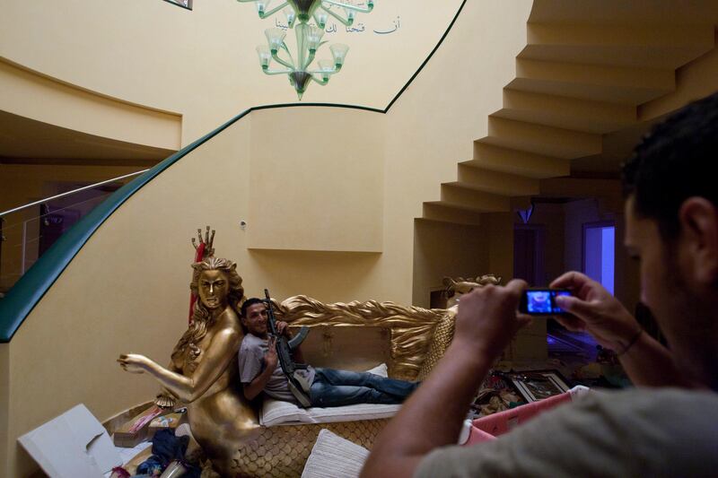 Rebel fighter pose for a photo as he  sit on a two seater couch that framed by golden mermaid with the face of Aisha Gadhafi the daughter of Libyan dictator Moammar Gadhafi in her house in Tripoli, Libya, Wednesday, Aug. 24, 2011. A defiant Moammar Gadhafi vowed Wednesday to fight on "until victory or martyrdom," as rebel fighters tried to end scattered attacks by regime loyalists in the nervous capital. (AP Photo/Sergey Ponomarev) *** Local Caption ***  Mideast Libya.JPEG-073a9.jpg