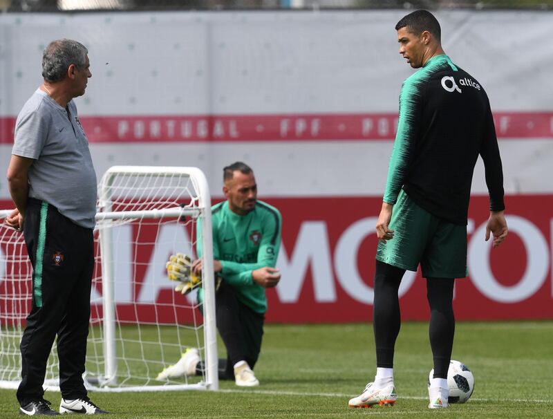 Portugal's head coach Fernando Santos, left, talks to forward Cristiano Ronaldo, right, as goalkeeper Beto Pimparel stretches during a training session at their base camp in Kratovo, Moscow, Russia, on June 12, 2018. Francisco Leong / AFP