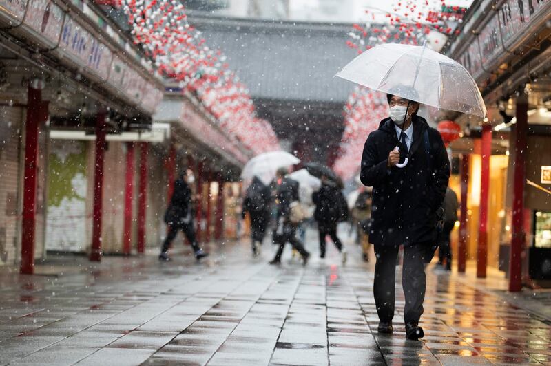 A man wearing a face mask walks through the Sensoji temple in the snow in Tokyo. AP Photo
