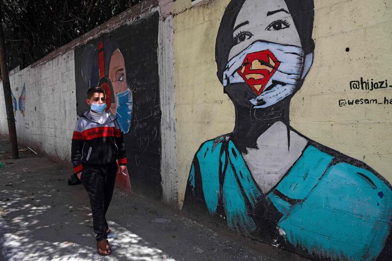 A Palestinian boy walks past a mural inspired by the coronavirus pandemic, in a street in Gaza City. AFP