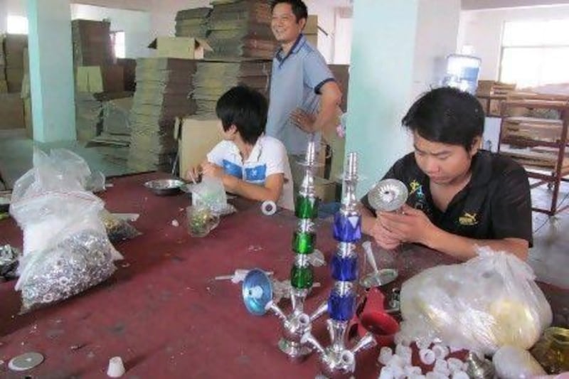 Luo Weiguo (standing) at his company's shisha pipe business in Dongyang. Mr Luo says the turmoil in the Middle East has resulted in falling demand for his pipes.