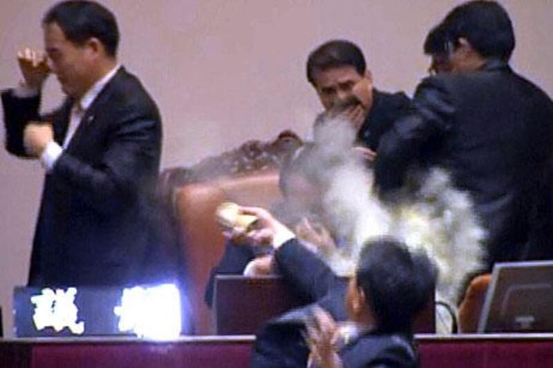 A member of the opposition Democratic Labor Party throws tear gas towards the speaker in South Korea's National Assembly in an attempt to block the ratification of a free trade bill with the US from passing.