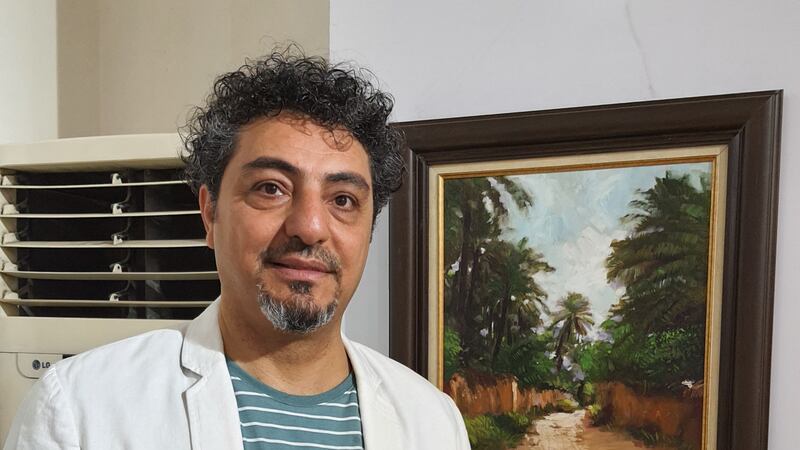 Artist Ziyad Jassam stands next to his oil on canvas painting which shows what is left in the once-lush Arab Jibour suburb in south-east Baghdad. 