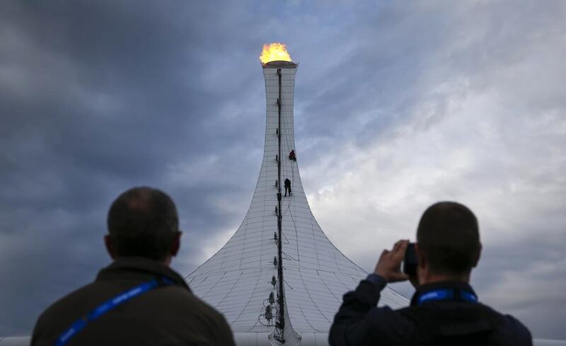 People watch as workers conducting maintenance rappel down on ropes from the top of the the Olympic Cauldron on Monday. Shamil Zhumatov / Reuters
