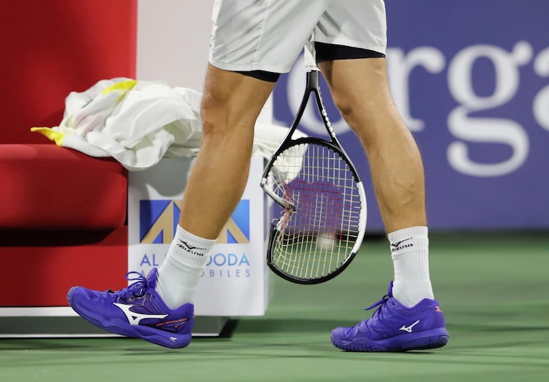 Philipp Kohlschreiber carries a broken tennis racquet back to his chair. Reuters