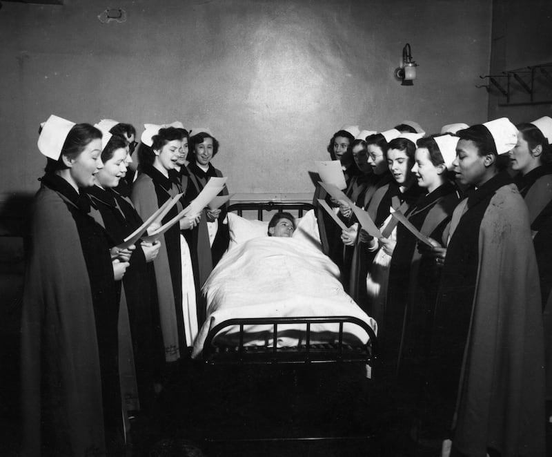 Nurses of Whipps Cross Hospital, in London, singing Christmas carols to one of the patients in bed in 1952. Getty Images