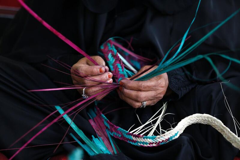 An Emirati woman weaves palm fronds.