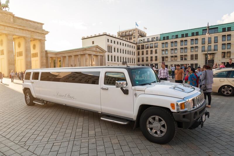 Berlin, Germany - August 12, 2014: Summer afternoon at the Brandenburger Tor - Berlin - Pariser Platz.  A lot of people / tourists looking around, taking Selfies or making photos of the area. In the forerground a white streching limousine for tourists
