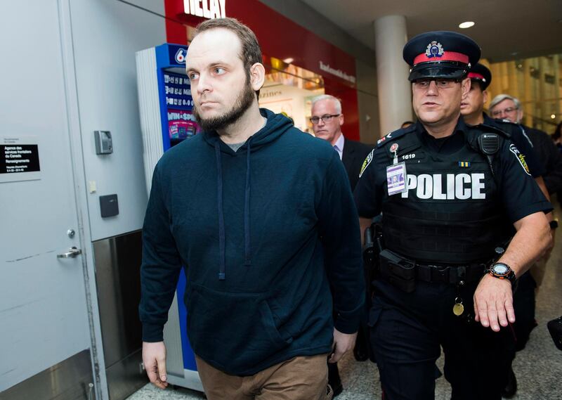 Joshua Boyle, left, gets a police escort after speaking to the media after arriving at the airport in Toronto on Friday, Oct. 13, 2017. Boyle, his wife Caitlin Coleman, and their three children landed in Canada after they were kidnapped in Afghanistan while on a backpacking trip and held hostage for five years by the Taliban-linked Haqqani network. (Nathan Denette/The Canadian Press via AP)