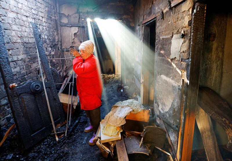 A woman stands in the shell of her neighbour's home, which was destroyed during shelling of Olenivka village, near Donetsk, in Russian-controlled Ukraine. Reuters