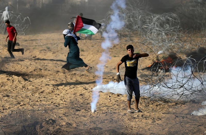 Palestinians react to tear gas fired by Israeli troops during a protest at the Israel-Gaza border in the southern Gaza Strip on July 13, 2018. Reuters