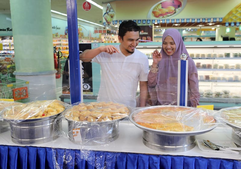 Abu Dhabi, United Arab Emirates - May 05, 2019: Rahmat Putra and Fitria Dawe look at the different sweets. People shopping for Ramadan. Sunday the 5th of May 2019. Al Wahda Mall, Abu Dhabi. Chris Whiteoak / The National