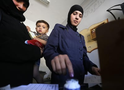A woman dips her index finger in ink after casting her ballot for Syria's first local elections since 2011, on September 16, 2018 in the southern Eastern Ghouta, on the eastern outskirts of the capital Damascus. Polling booths opened at 7:00 am (0400 GMT) across government-held parts of the country and will be open for 12 hours, with a potential five-hour extension depending on turnout, reported state news agency SANA. / AFP / LOUAI BESHARA
