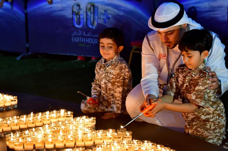 A man and two children light candles after the building lights were switched off for the Earth Hour environmental campaign in Dubai on March 24, 2018.
Earth Hour, which started in Australia in 2007, is set to be observed by millions of supporters in 187 countries, who will turn off their lights at 8.30pm local time in what organisers describe as the world's "largest grassroots movement for climate change". / AFP PHOTO / Giuseppe CACACE